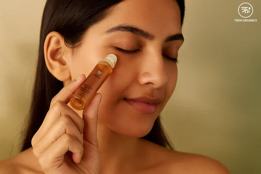 Woman applying Trehi Organics flaxseed roll-on under the eyes, highlighting a soothing ritual for puffy eyes and dark circles.